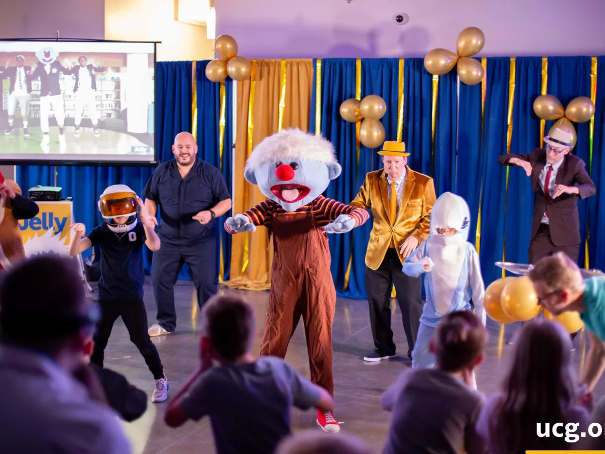 people in costume dancing on a stage with children watching