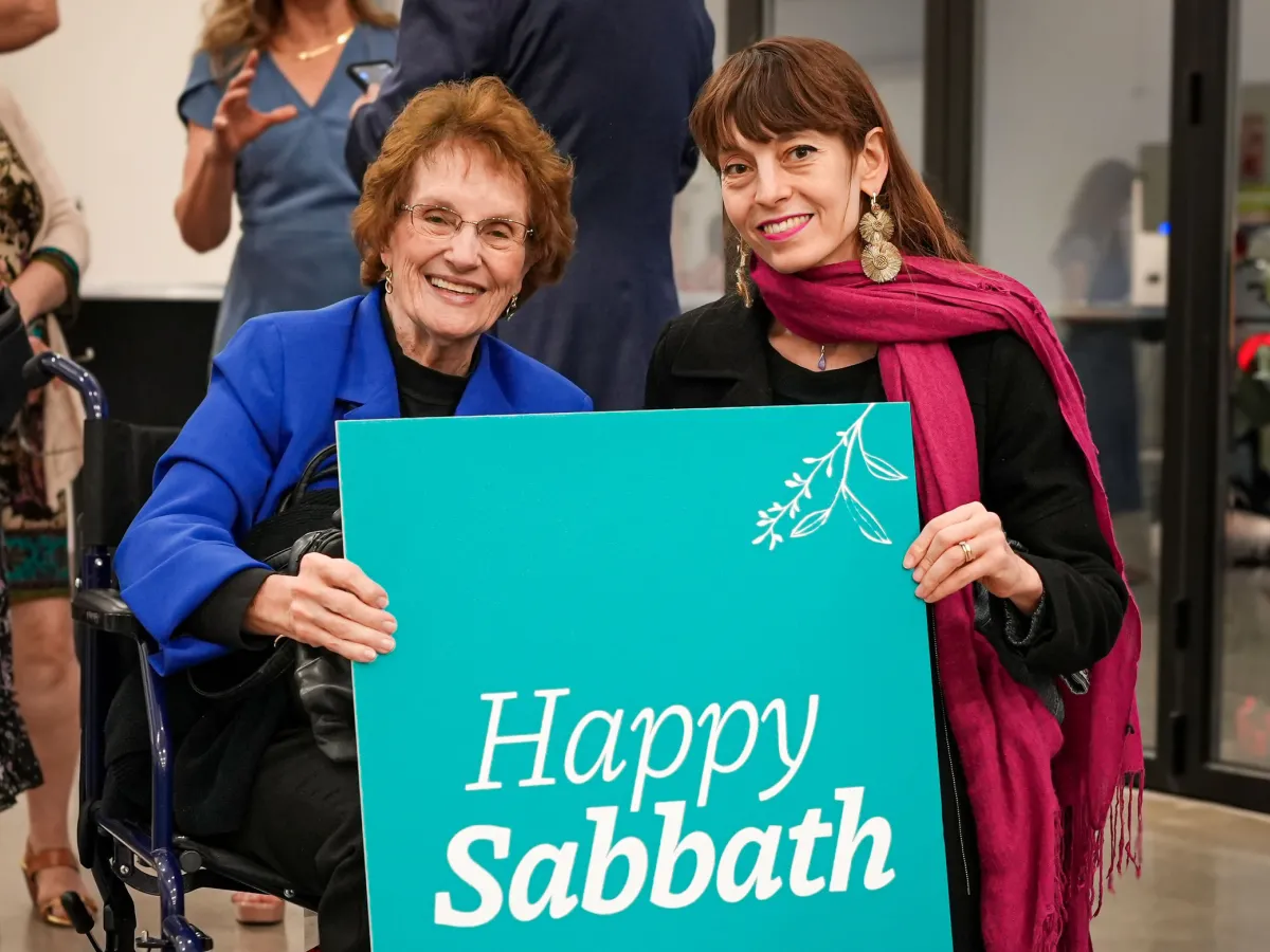 two women holding a "Happy Sabbath" sign