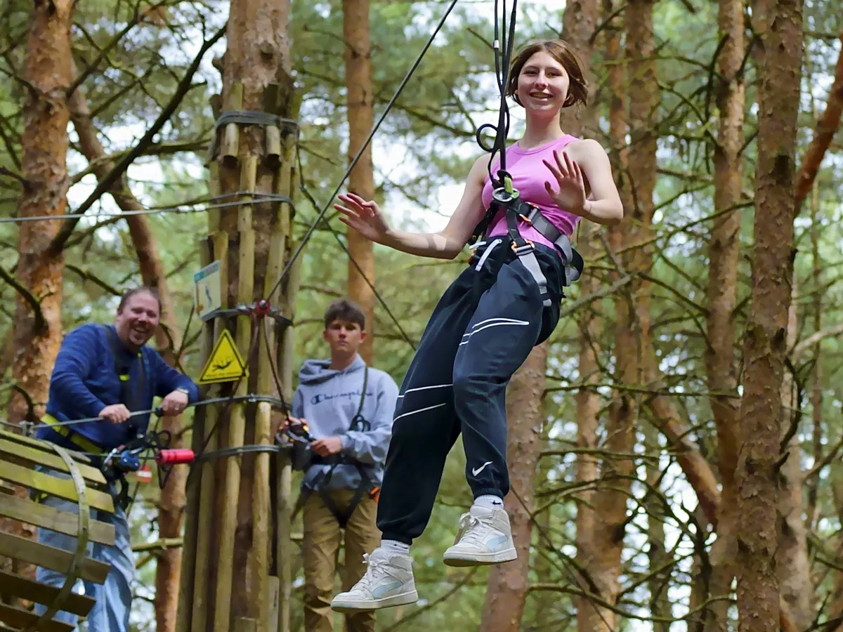 teenagers doing a climbing course wearing a rope harness