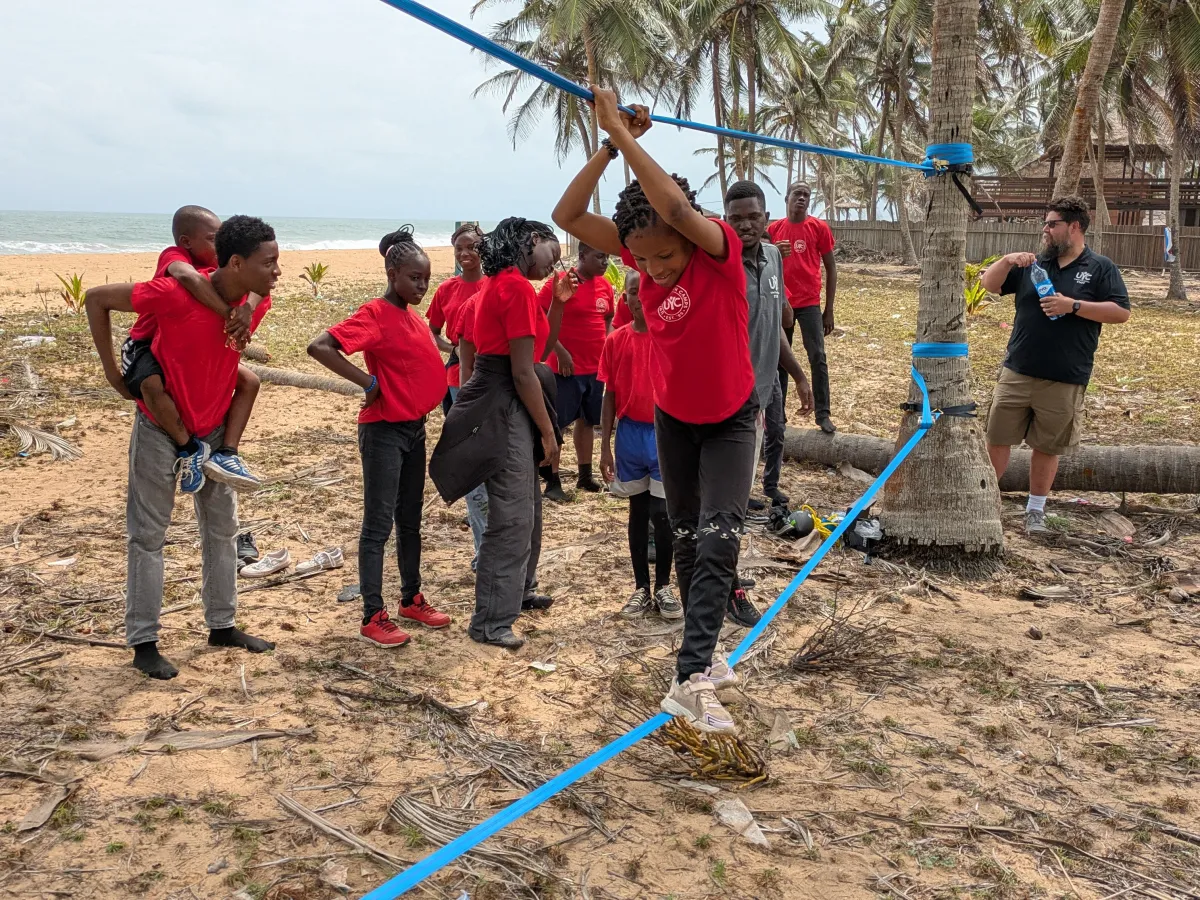 teenagers wearing red shirts and completing a low ropes activity