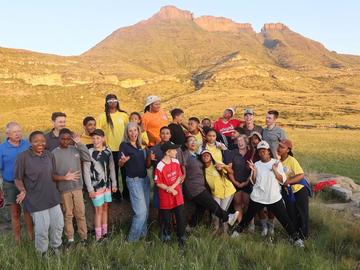 a group of people standing in front of low rolling mountains