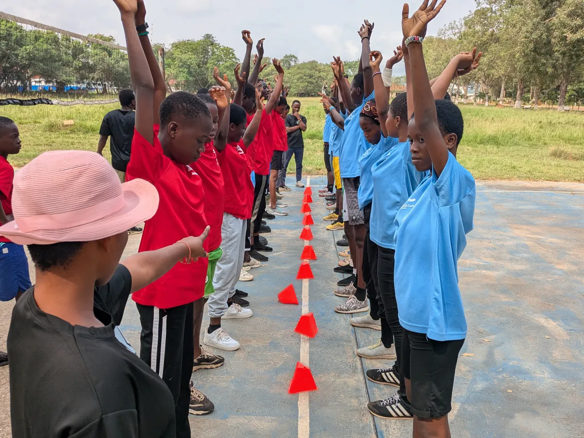 two teams of young people standing on opposite sides of a line with arms in the air