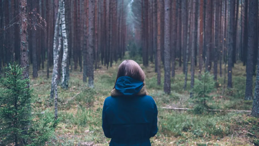 A young woman looking into a forest.