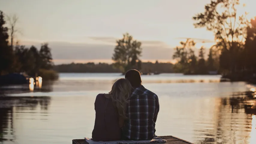 A couple sitting beside each other on a boat dock.