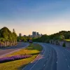 a two-sided highway running through a green landscape with historical buildings, and a cityscape in the background
